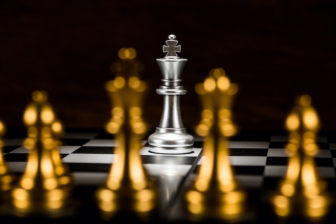 single-silver-king-chess-surrounded-by-number-gold-chess-pieces